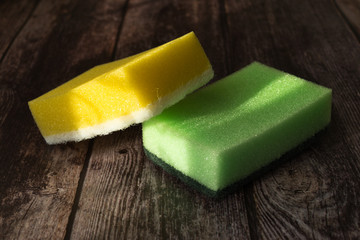 Cleaning equipment: cloth, plastic bottle and sponges, in the wooden background