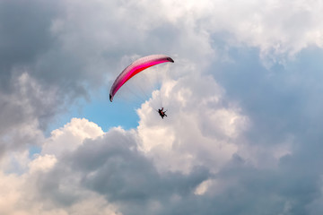 Paraglider flying through the sky against the clouds