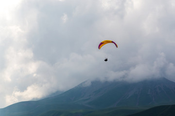 Paraglider flying over a mountain pass