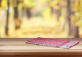 empty table with red towel on autumn background. copy space.