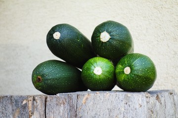 Heap of green ripe zucchini on a wooden log. Healthy seasonal vegetable.