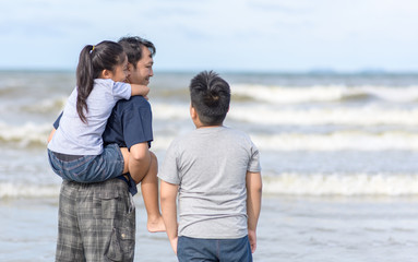 father and two kids walking on beach