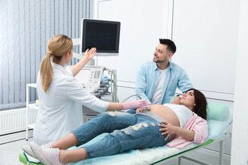 Man supporting his wife during ultrasound scan in clinic