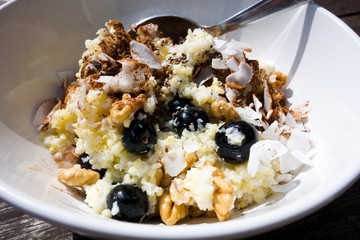 Healthy hot breakfast. Bowl of millet porridge with blueberries, coconut, walnuts and cinnamon. Closeup.