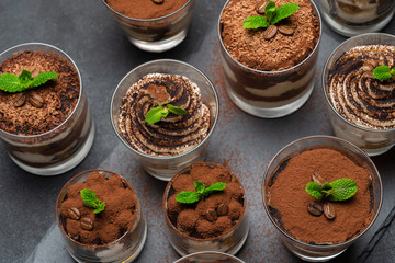 Group of portions of Classic tiramisu dessert in a glass cup on stone board on concrete background