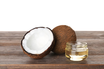 Coconuts and jar of natural organic oil on wooden table against white background