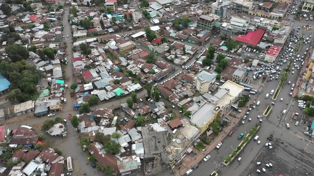 Tilting aerial footage of homes and stores (mostly with rooftops made of corrugated sheet) in central Gondar city, Ethiopia
