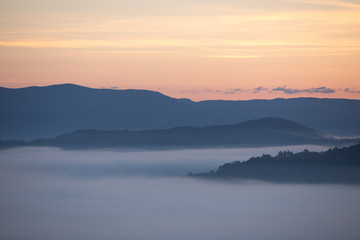 Naklejka na ściany i meble view of sunrise over the mountains mist and clouds under peaks
