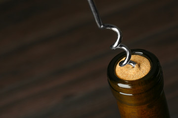 Bottle of wine and corkscrew on dark background, space for text