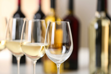 Row of wine glasses and blurred bottles on background, space for text