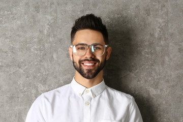 Portrait of handsome smiling man in glasses on grey background