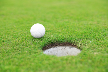 Golf ball near hole on green course