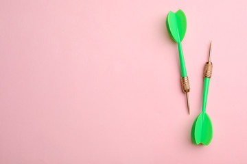 Green dart arrows on pink background, flat lay with space for text