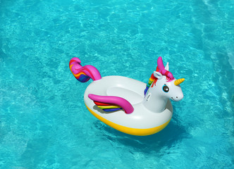 Funny inflatable unicorn ring floating in swimming pool on sunny day. Space for text