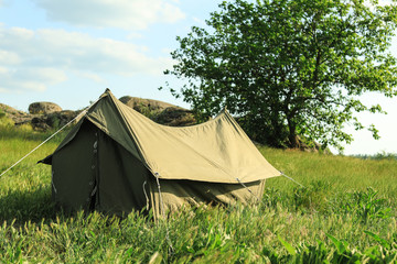 Camping tent in green field on sunny day. Space for text