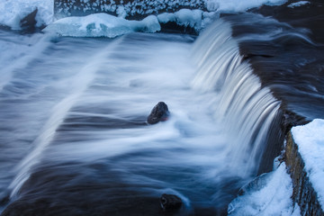 rapids of a waterfall, taken with a long exposure from a tripod in winter with islands of ice and snow