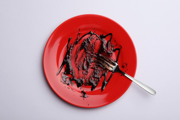 Dirty plate with food leftovers and fork on white background, top view