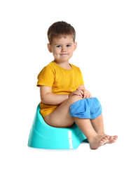 Portrait of little boy sitting on potty against white background