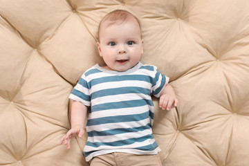 Portrait of cute little child lying on beige pillow, top view