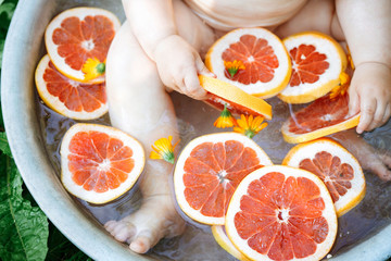 Baby taking a fruit bath outside in a basin