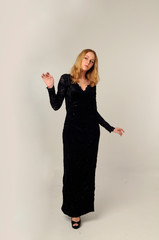 full length portrait of blonde woman wearing long  lace gown, standing pose against a creamy studio background.