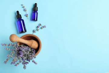 Bottles of essential oil, mortar and pestle with lavender flowers on light blue background, flat...