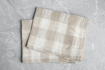 Beige plaid kitchen towels on light marble background, top view