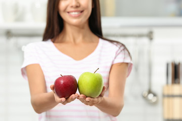 Woman holding fresh apples in kitchen, closeup