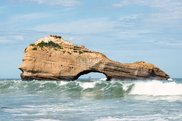 Miramar beach in Biarritz with a rock and a sailboat in the middle. - obrazy, fototapety, plakaty