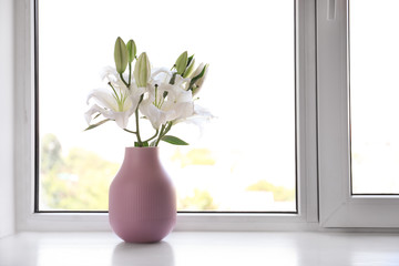 Vase of beautiful lilies on windowsill indoors, space for text