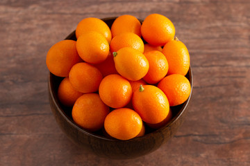 Bowl of Fresh Kumquats on a Rustic Wooden Table