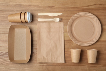 Flat lay composition with new paper dishware on wooden background. Eco life