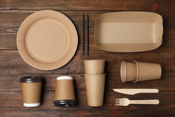 Flat lay composition with new paper dishware on wooden background. Eco life