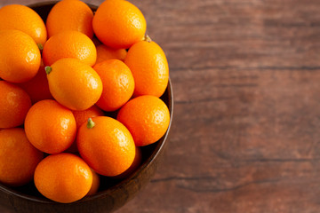 Bowl of Fresh Kumquats on a Rustic Wooden Table