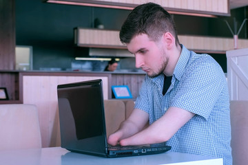 Computer online job. Disabled man freelancer with amputated two stump hands in cafe typing works on...