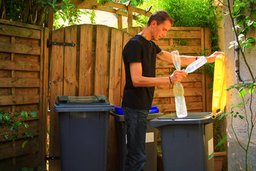 Person making a selective sorting of waste. Man putting plastic bottles in a yellow bin for recycling.