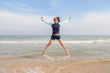Obraz premium Asian women in bathing suits are jumping on the sand. Thai teenagers are playing at the beach during the daytime.