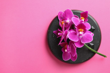 Spa stone and beautiful orchid flowers on pink background, top view. Space for text