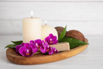 Obraz na płótnie Canvas Tray with orchid flowers, candles and soap on white wooden table