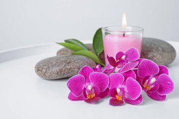 Spa stones, orchid flowers and candle on white table