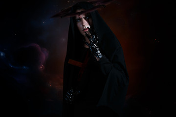 Evil demon with a nimb and cross with black glossy hands and big claws. Standing in black robe on a space background - obrazy, fototapety, plakaty