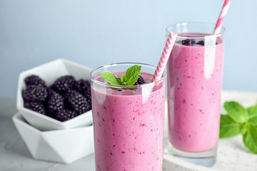 Delicious blackberry smoothie in glasses on light table