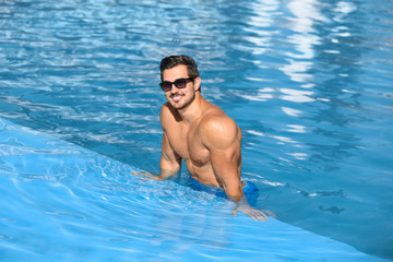 Handsome young man in swimming pool on sunny day