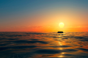 Refugees on a big rubber boat in the middle of the sea that require help. Sea with people in the...