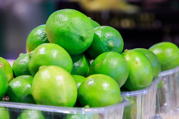Small lime lemons in plastic bowls put up for sale at the Boqueria market. Food concept