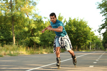 Obraz premium Handsome young man roller skating in park