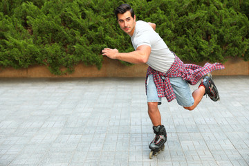 Handsome young man roller skating outdoors. Recreational activity