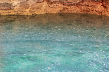 Karst lake in a mountain cave. Sulfurous lake. Beautiful natural texture and turquoise background of the lake combined with gold stone.