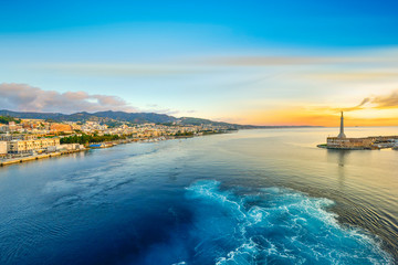 Sunrise from a cruise ship at the port of Messina, Italy on the island of Sicily in the Mediterranean Sea with the Golden Madonna della Lettera column in view - obrazy, fototapety, plakaty