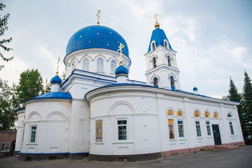 Christian Church of white stone with blue domes with stars and gold crosses. Holy Trinity Church in Tomsk, Russia.